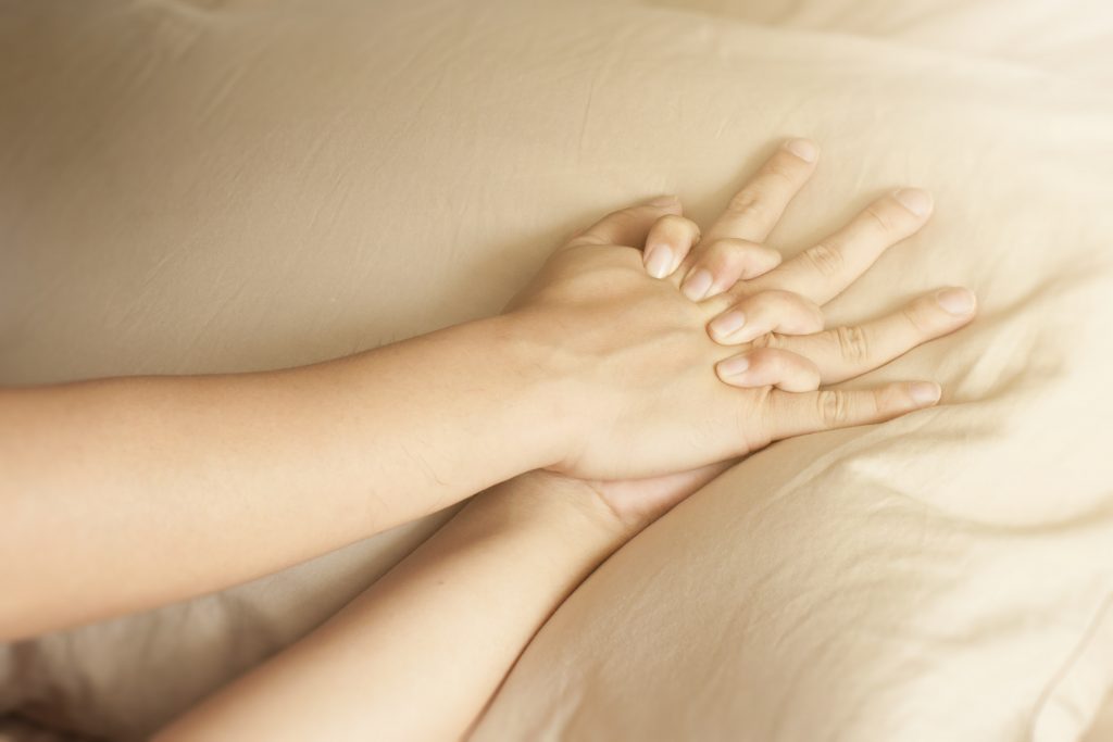 Close up hands of a couple having sex on a bed